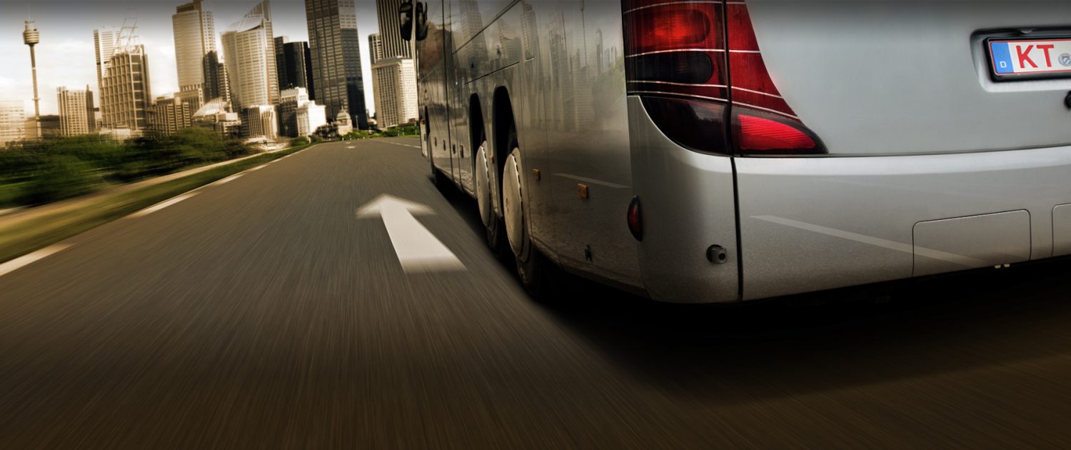 Reisebus mit rotem Überführungskennzeichen vor einer Skyline